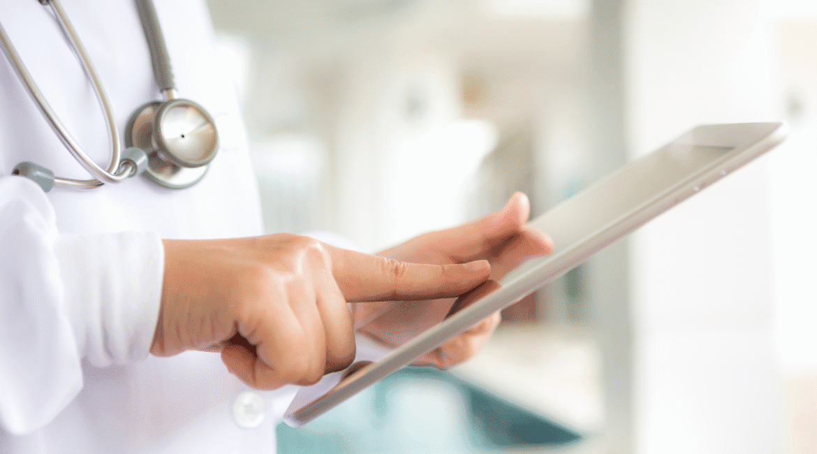 Médico utilizando um tablet em ambiente clínico, representando o uso de tecnologia no marketing para médicos de forma ética e profissional.