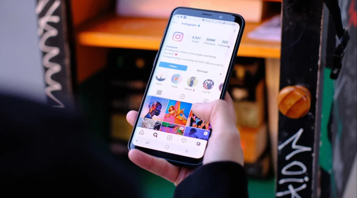 Pessoa segurando um celular aberto no aplicativo do Instagram, ilustrando a atualização do Instagram 2025 e suas novas funcionalidades para perfis e engajamento.