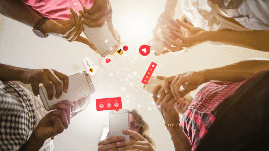 Grupo de pessoas segurando celulares com ícones de curtidas e comentários flutuando, simbolizando o engajamento e as interações nas redes sociais.
