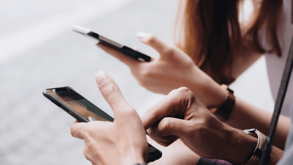 Duas pessoas usando smartphones enquanto interagem online, representando conexões e engajamento no marketing de comunidade.
