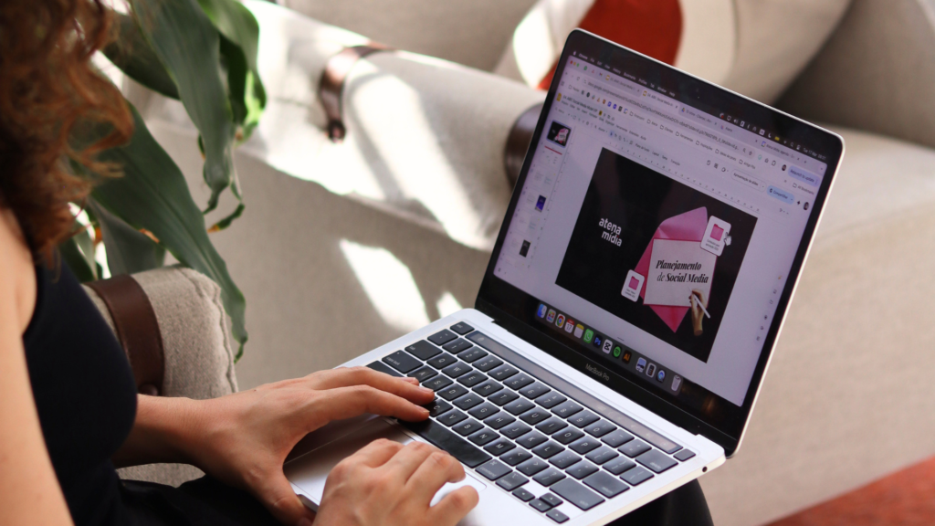 Mulher utilizando notebook em ambiente confortável, com apresentação aberta na tela, representando planejamento, estratégia e desenvolvimento de negócio.