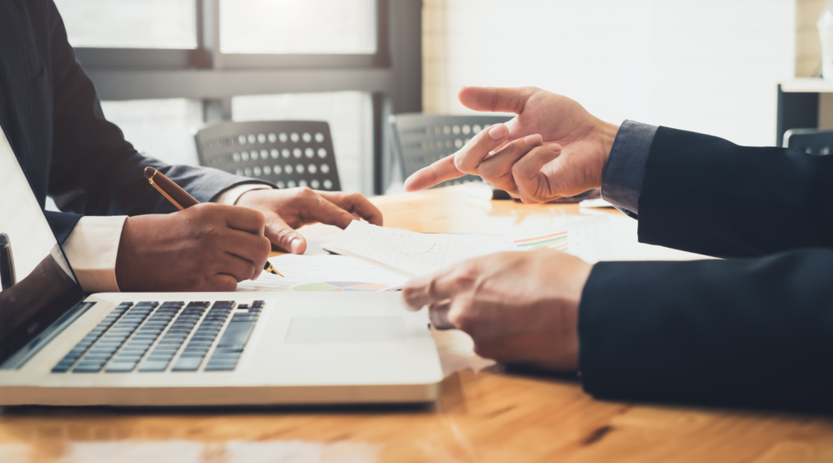Profissionais reunidos em uma reunião de negócios analisando documentos e discutindo estratégias, representando como a percepção de valor influencia a confiança, a tomada de decisão e o fechamento de contratos.