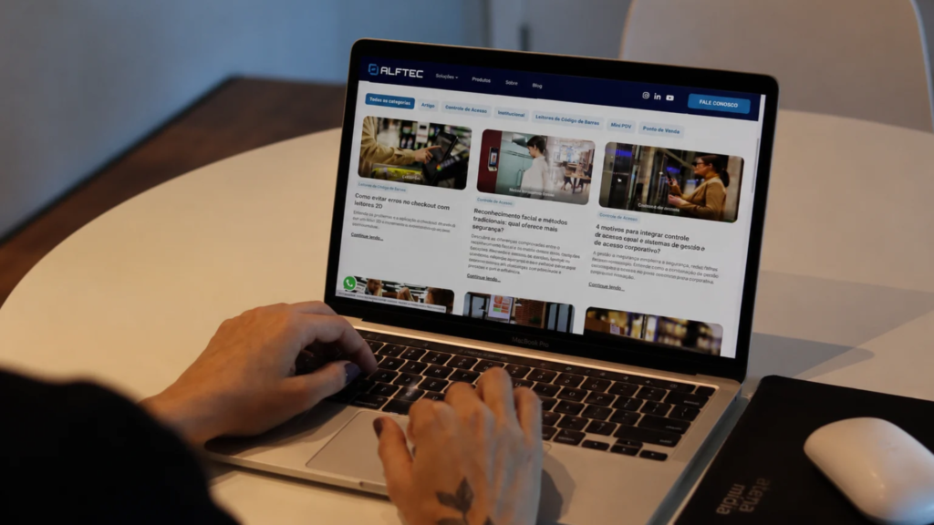 Equipe da Atena Mídia trabalhando em um notebook em ambiente corporativo, com o site da ALFTEC aberto na tela, representando a construção de relevância e presença digital de empresas B2B.
